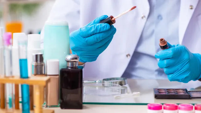 Tecnico di laboratorio intento a prelevare una piccola quantità di un correttore per poter effettuare le analisi che solitamente si effettuano sui decorative cosmetics